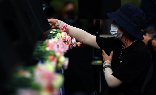 서울 서이초등학교 교사의 49재 추모일인 4일 오후 서울 여의도 국회 앞에서 열린 추모 집회에서 참가자가 헌화하고 있다. 이날 집회 시작 전 참가자들은 천송이의 꽃을 헌화했다. [연합뉴스]